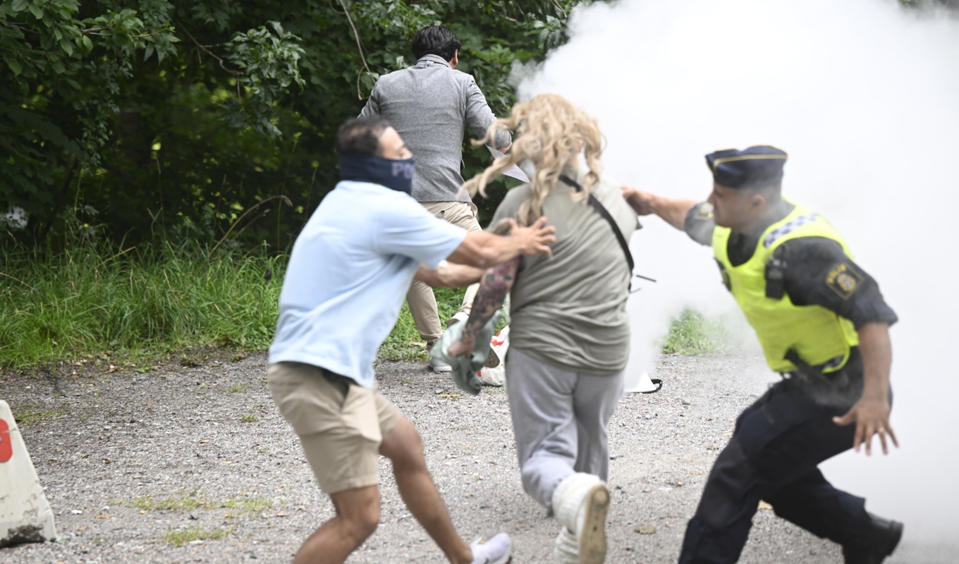 En kvinna sprang fram och försökte med en brandsläckare släcka elden på den koran som Salwan Momika antänt utanför Irans ambassad på Lidingö. Foto: Fredrik Sandberg/TT