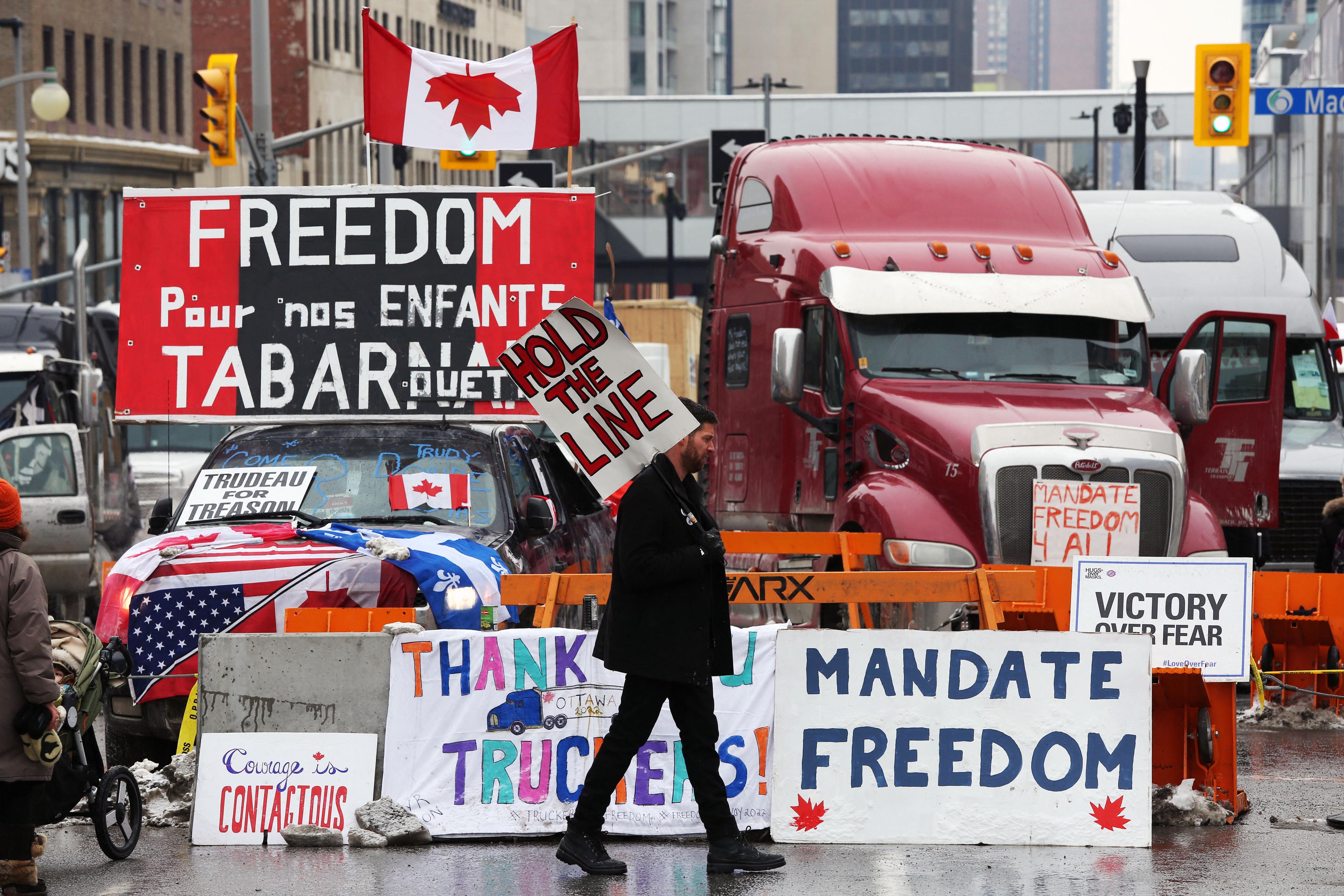 En demonstrant går förbi lastbilar i samband med Frihetskonvojen i Ottawa i Kanada den 8 februari 2022. Foto: Dave Chan/AFP via Getty Images
