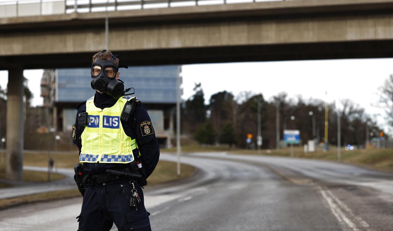 Polis i gasmask vid Säkerhetspolisens högkvarter i Solna norr om Stockholm. Foto: Fredrik Persson/TT