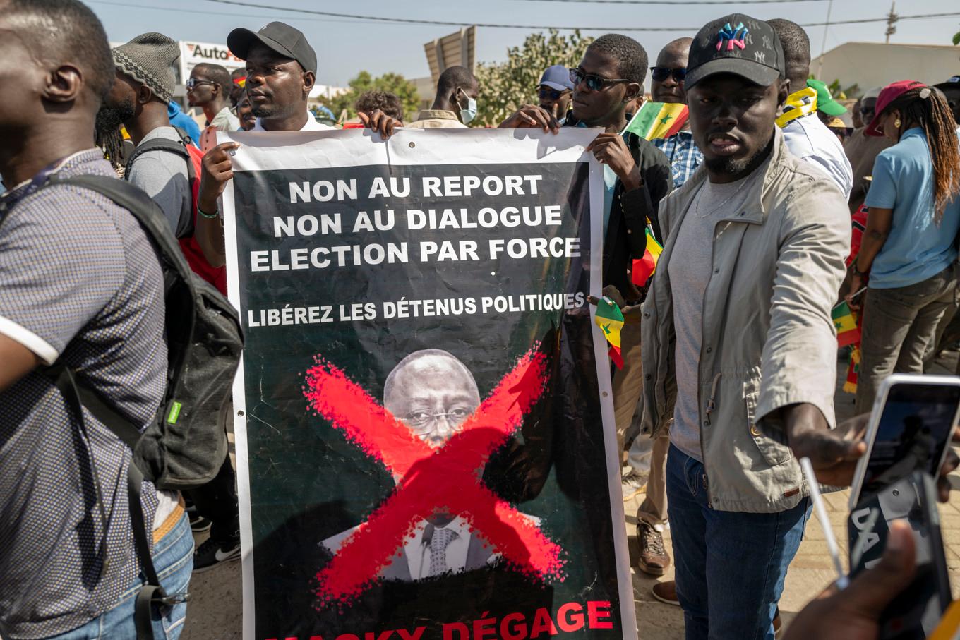 Anhängare av oppositionen i Senegal protesterar på gator i Dakar med en skylt där det står "Nej till fördröjning, nej till dialog, val med tvång". Foto: Sylvain Cherkaoui/AP/TT
