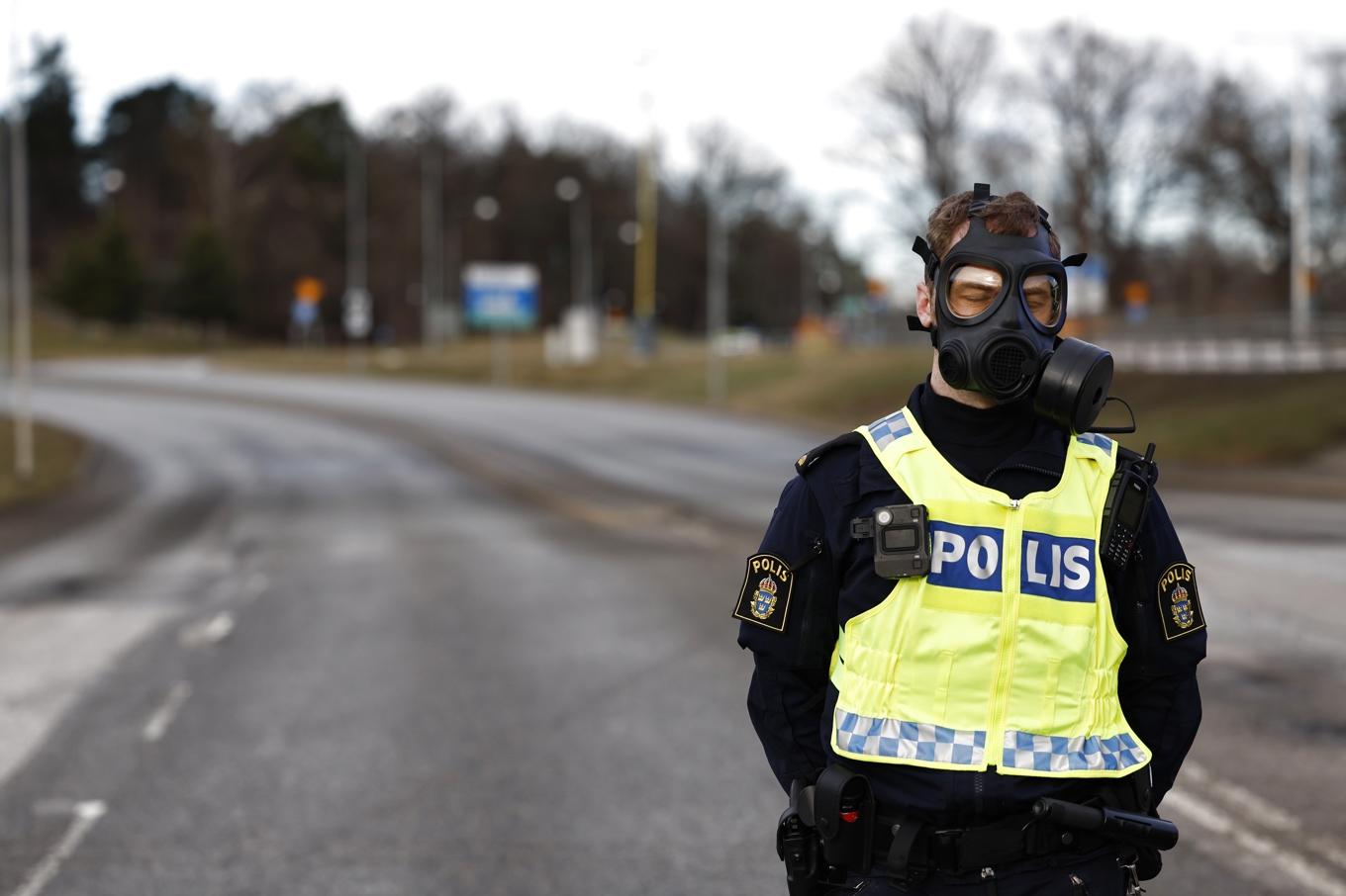 Polis i gasmask vid Säkerhetspolisens högkvarter i Solna norr om Stockholm under fredagen. Foto: Fredrik Persson/TT