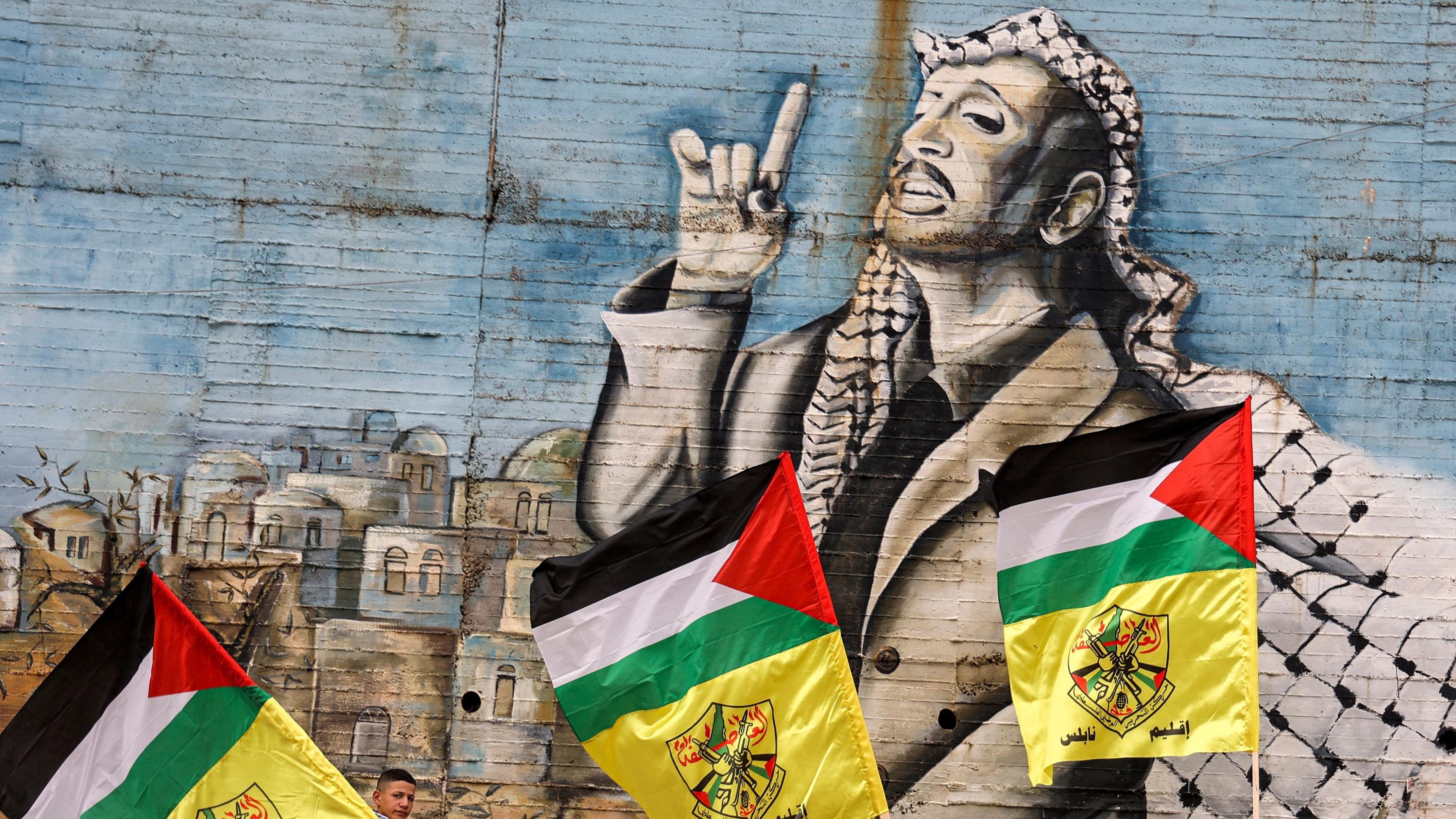 Medlemmar av al-Fatah går förbi en målning av PLO-ledaren Yassir Arafat på Västbanken. Socialdemokraternas palestinska engagemang går långt tillbaka. Foto: Jaafar Ashtiyeh/AFP via Getty Images