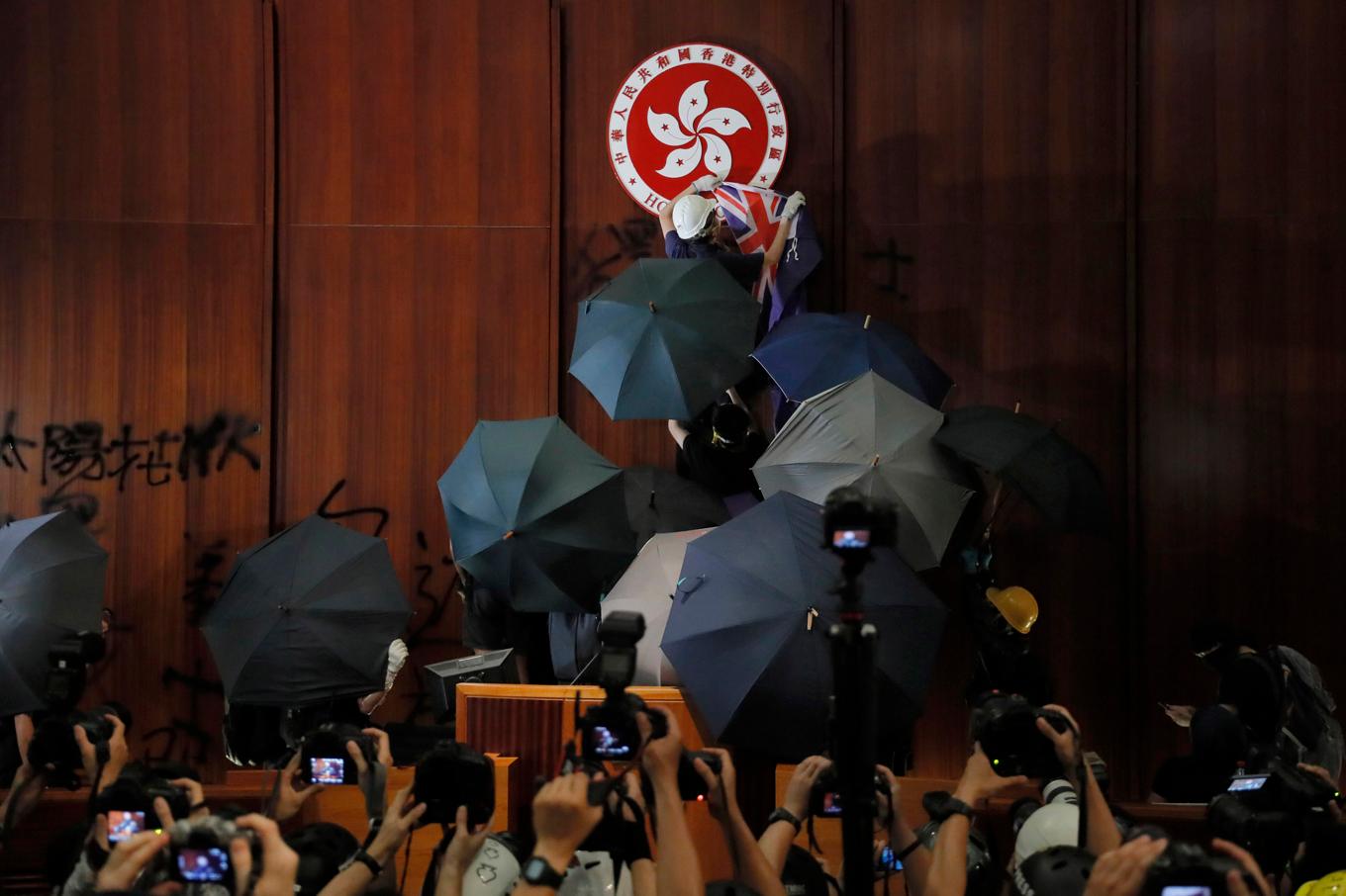 Utrustade med paraplyer och färgglada skyddshjälmar tog sig demonstranterna in i parlamentsbyggnaden 1 juli 2019. Arkivbild. Foto: Kin Cheung/AP/TT