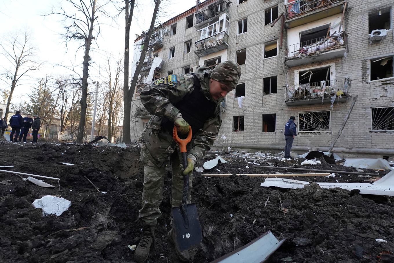 En polis framför ett förstört bostadshus i Charkiv. Foto: Andrii Marienko/AP/TT