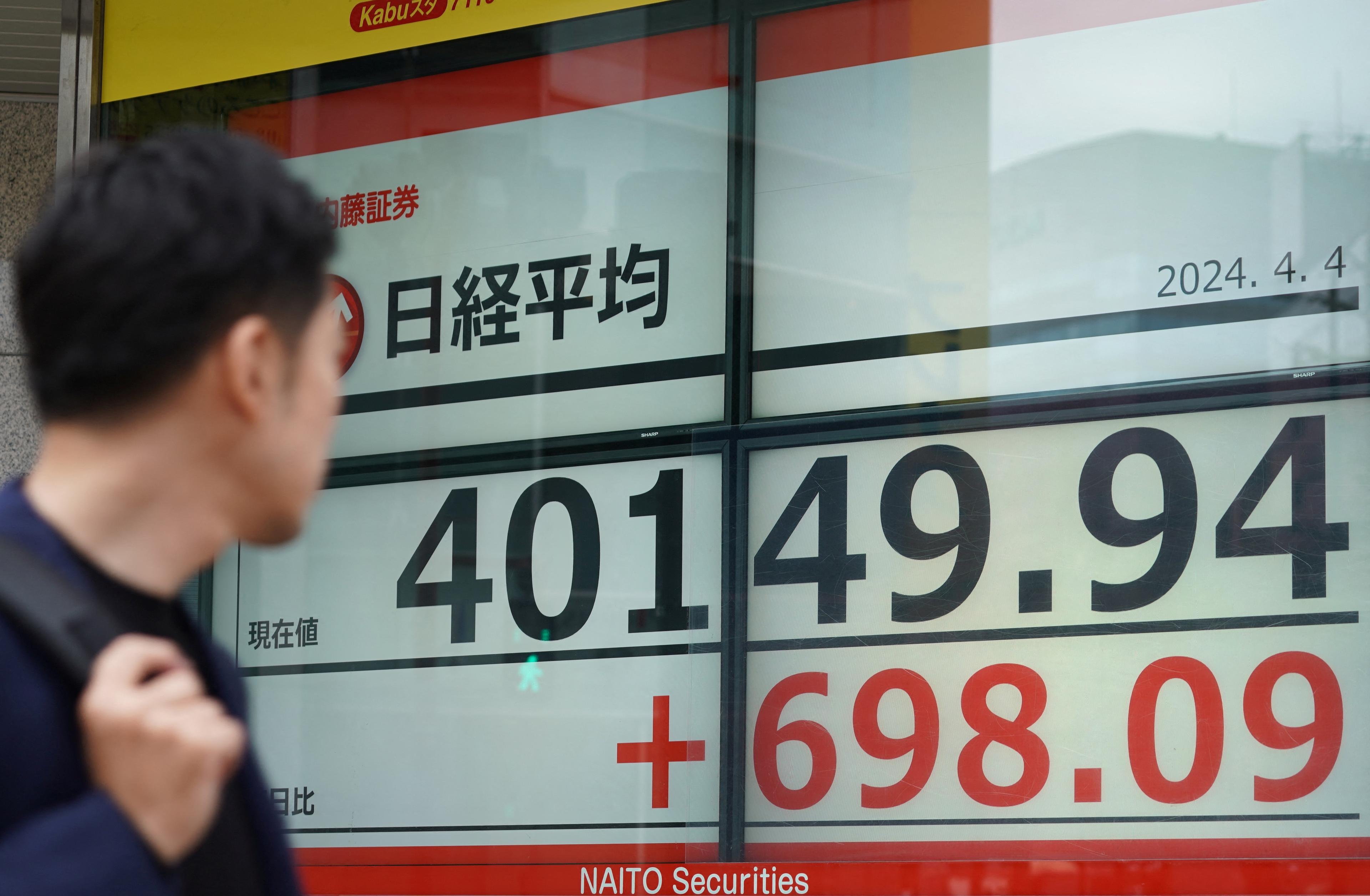 En man tittar på en elektronisk tavla som visar aktiekursen för Nikkei-indexet på Tokyobörsen i Tokyo i Japand den 4 april 2024. Foto: Kazuhiro Nogi/AFP via Getty Images