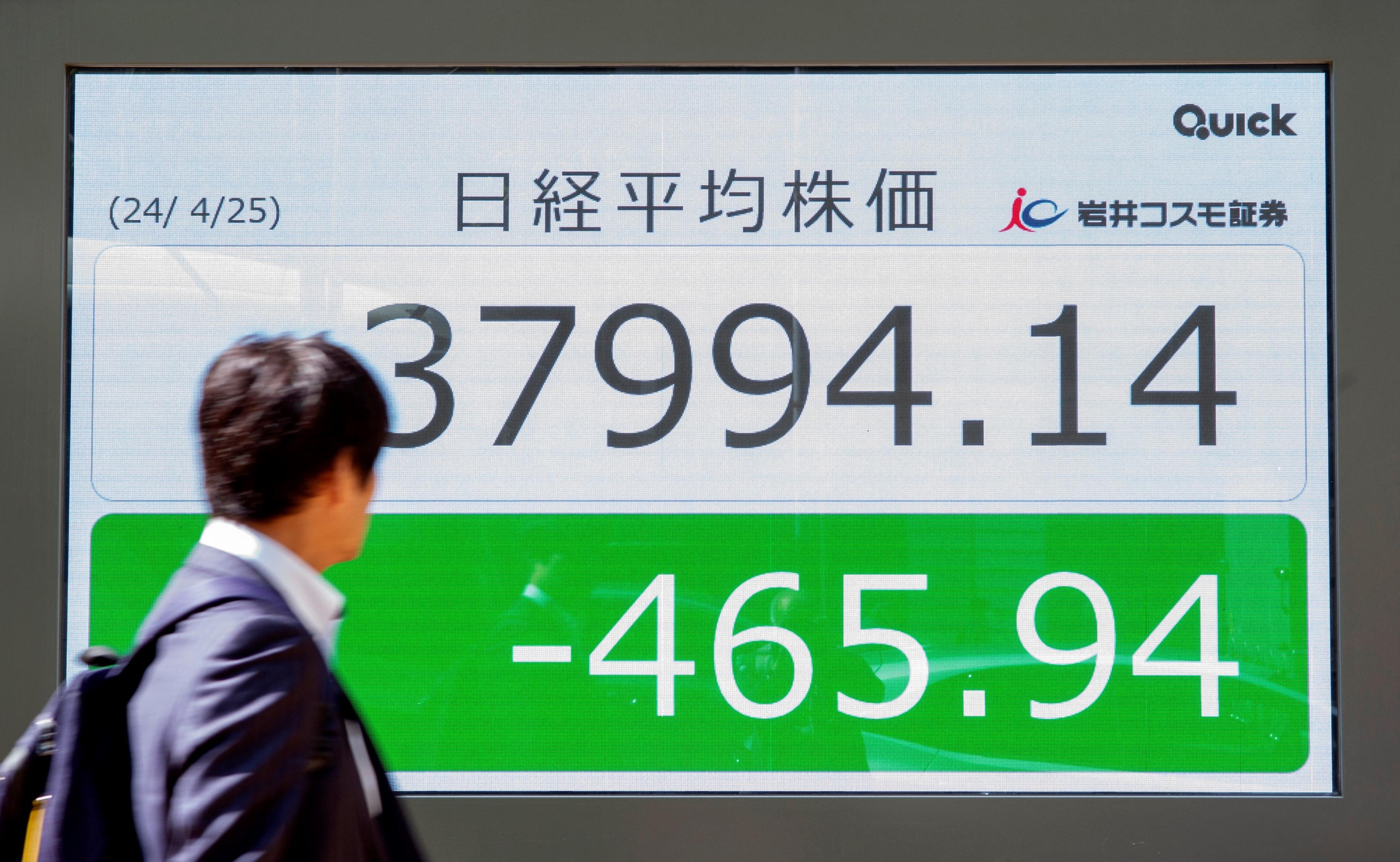 En man går framför en elektronisk tavla som visar aktiekursen för Nikkei-index på Tokyobörsen längs en gata i Tokyo den 25 april. Foto: Kazuhiro Nogi/AFP via Getty Images