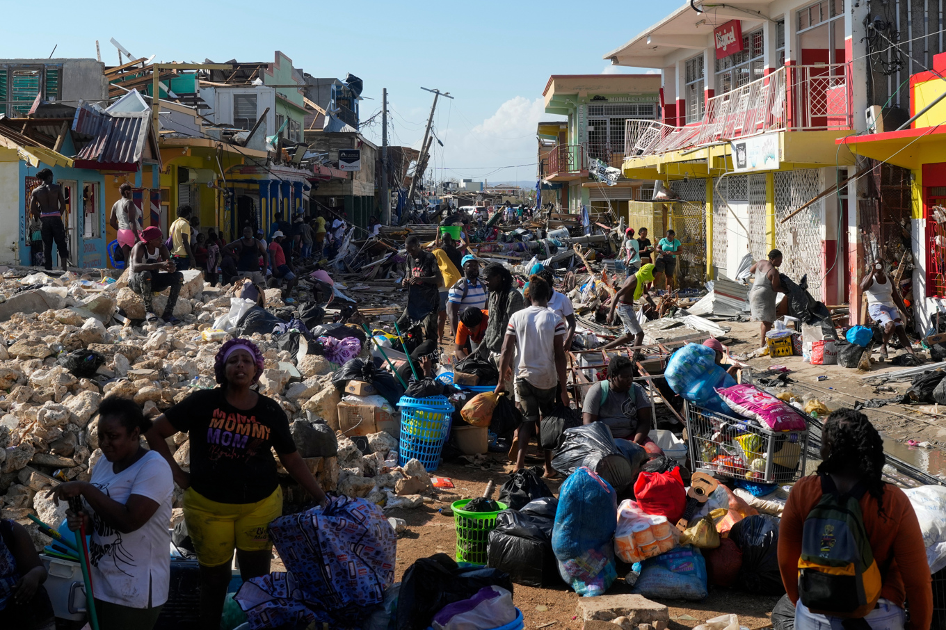 Boende samlas bland bråte efter Melissas framfart i orten Black River på Jamaica under torsdagen. Foto: Matias Delacroix/AP/TT