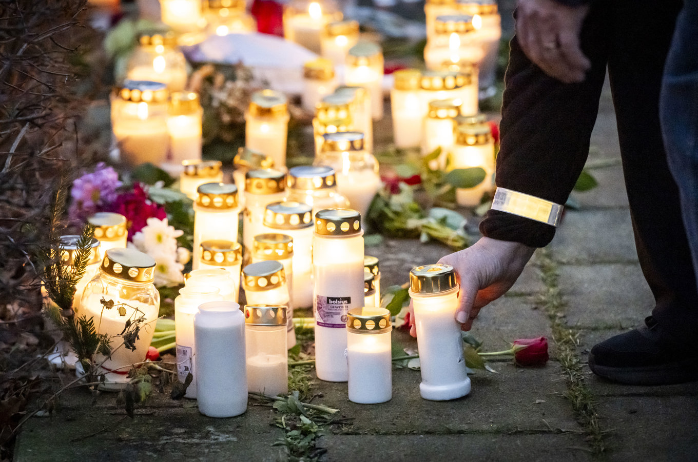 Fler personer har lämnat blommor och tänt ljus vid minnesplatsen utanför bostaden där en kvinna och ett barn hittades döda i tisdags. Foto: Johan Nilsson/TT