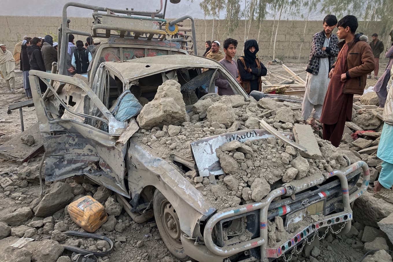 Lokalbefolkning invid en bil som träffats i de pakistanska attackerna mot den afghanska provinsen Nangarhar. Foto: Hedayat Shah/AP/TT