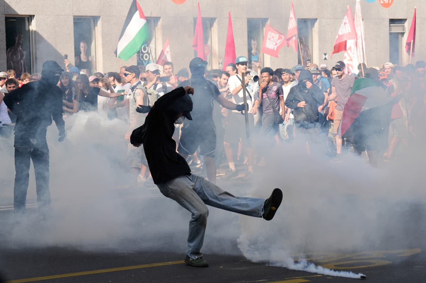 En demonstrant sparkar under en tårgasburk under protesten i Genève på söndagen. Foto: Baz Ratner/AP/TT