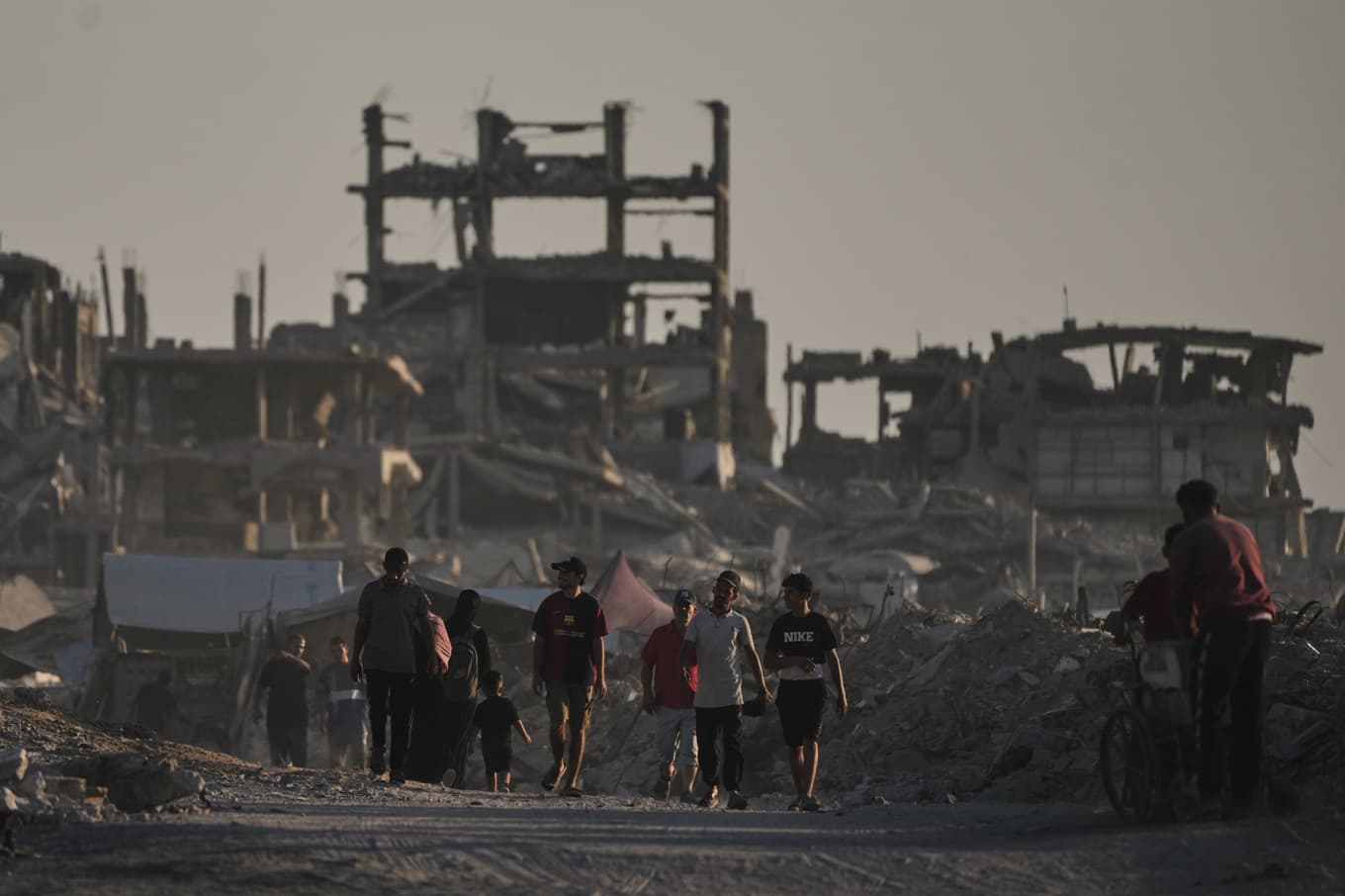 Palestinier framför en bombad byggnad i Gaza stad, där hjälpbehovet är enormt, under måndagen. Foto: Jehad Alshrafi/AP/TT