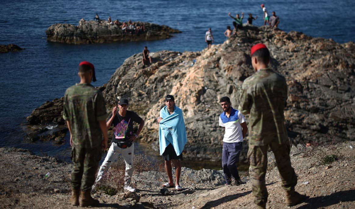 Spanska soldater talar med en grupp migranter vid den spanska exklaven Ceuta den 2 augusti i år. Foto: Henry Nicholls/AFP via Getty Images