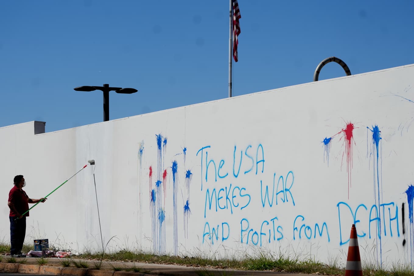 En man sanerar graffiti på muren till USA:s ambassad i huvudstaden Brasilia. Arkivbild. Foto: Eraldo Peres /AP/TT