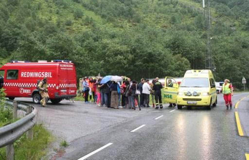 Bilförare och passagerare står vid en brandbil den 5 augusti efter att de evakuerats vid en brand som uppstått i tunneln nära Gudvangen, västra Norge. (Foto: Arne Veum / NTB scanpix / AFP)
