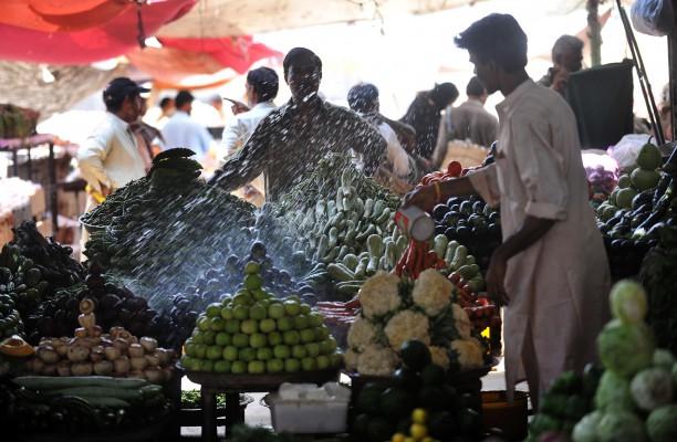 En pakistansk grönsaksförsäljare köpslår med en kund på marknaden i Karachi. Pakistans fridfulla vardagsliv rapporteras det sällan om i världen, enligt skribenten. (Rizwan Tabassum/AFP/Getty Images)
