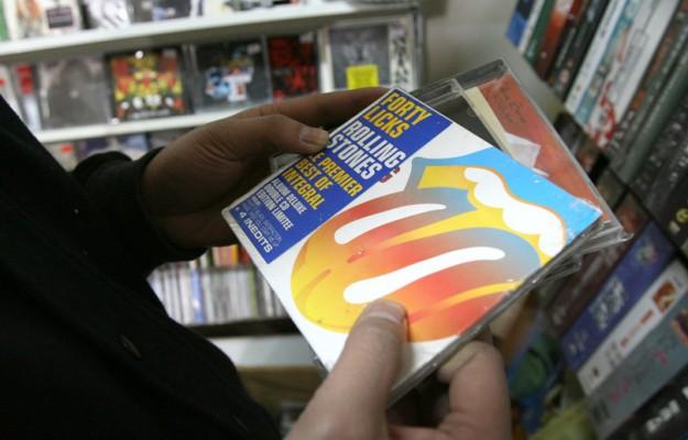 En kund tittar på falska CD-kopior av Rolling Stones i en piratbutik med dvd i Shanghai. (Foto: AFP / Mark Ralston)
