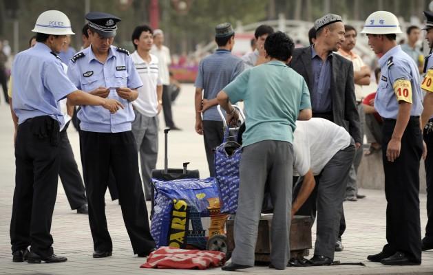 Poliser kollar id-handlingar och letar igenom uighurers väskor i Östturkestan, officiellt Uiguriska autonoma regionen Xinjiang.  Regionen har en betydande uigurisk befolkning (45 procent). (Foto: AFP / Peter PARKS)