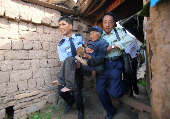 Hjälparbetare bär 10 juli ut en kvinna som drabbades av jordbävningen dagen före. 400 000 människor uppges enligt AFP ha evakuerats från sina hem i Yunnanprovinsen (Foto: AFP)
