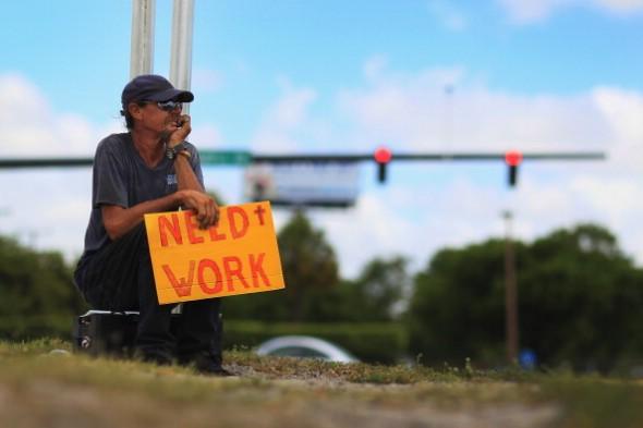 En man håller upp en skylt och hoppas på att hitta ett jobb som grovarbetare eller snickare, i Pompano Beach, Florida. (Foto: Joe Raedle / Getty Images)