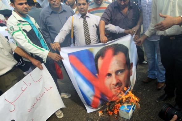 Demokratiaktivister bränner den syrianske presidenten Bashar al-Assads porträtt vid en demonstration utanför Arabförbundets högkvarter i Kairo, där ett akut ministeriummöte hölls den 12 november 2011. (Foto: Khaled Desouki/ AFP)