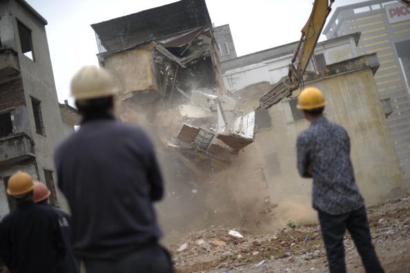 Arbetare vid en byggnad som rivs i byn Yangji i Guangdongprovinsen i södra Kina, den 21 mars 2012. Nyligen släpades ett par i Shandong ur sina sängar så att deras hus skulle kunna rivas mitt i natten, enligt kinesiska medierapporter. (Foto: STR/AFP/Getty Images)