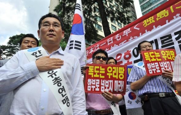 Sydkoreanska demonstranter saluterar nationella flaggor under en demonstration framför den japanska ambassaden i Seoul den 17 Augusti 2012 och fördömde Japans anspråk på den lilla kedjan av Seoul-kontrollerade klippiga öar, vilka kallas Dokdo i Korea och Takeshima i Japan. (Foto: Jung yeon-Je/AFP/Getty Images)