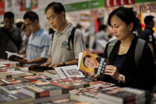 Besökare på en mässa i Hongkong den 18 juli 2012 blädrar i kinesiska politiska böcker. (Philippe Lopez/AFP/GettyImages) 
