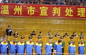 Kinesisk polis vaktar en grupp fångar den 25 maj 2001, utanför en domstol i Peking, innan de hämtades in för att få sina domar. Antalet avrättningar utförda i Kina var då fler än 1 000 under en sex veckor lång “slå hårt” kampanj initierad av den kommunistiskledaren Jiang Zemin. Han krävde att poliserna skulle öka takten på arresteringar, fällande domar och avrättningar. (Foto: AFP/Getty Images)
