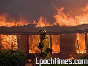 En brandman försöker släcka ett brinnande hus i Rancho Bernardo, Kalifornia. (Foton: Alex Li/The Epoch Times)
