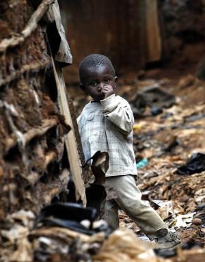 Ett barn i Kiberaslummen i Nairobi, Kenya, leker i den smutsiga dräneringskanalen som rinner mellan husen. På grund av hälsoriskerna immuniserar Nairobis statsråd byborna var tredje månad mot vattenrelaterade sjukdomar. (Foto: Marco Longari/AFP/Getty Images)