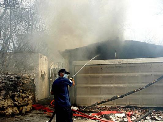 En man försöker släcka eldsvådan i sitt hus. (Foto: Eurokinissi/AFP/Getty Images)
