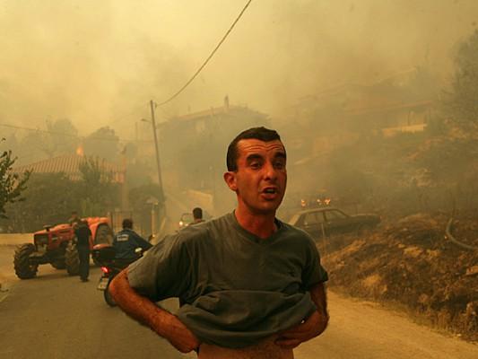 Människor flyr från en brinnande by nära det forntida Olympia, Platanos, Grekland. (Milos Bicanski/Getty Images)
