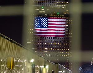 En amerikansk flagga ses genom de höga staketen som omger byggplatsen vid Ground Zero. (Foto: Genevieve Long/The Epoch Times)
