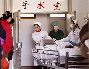 Familjemedlemmar ser på när sköterskor rullar in en patient på ett sjukhus i Kina. (Personerna på bilden har ingen direkt koppling till artikeln). (Foto: AFP/AFP/Getty Images)
