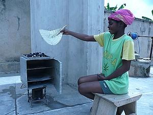 Ama Bohemaa visar hur denna smarta lilla konservburksugn används till bakning över en träkolsbrasa under söndagen i Kumasi, Ghana. (Foto: Zoe Ackah/ Epoch Times) 
