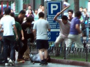 Bilden är en tv-bild från AFP. Hankineser attackarerar en ensam uigurisk man på en gata i Urumqi, Xinjiang den 8 juli 2009. (Foto: Sam Beattie/AFP /AFPTV) 
