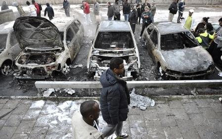 Invånare i Rinkeby beskådar utbrända bilar, ett resultat av ungdomsupploppen i Stockholms förorter vilket spred sig ut i landet. (Foto: Jonathan Nackstrand / AFP)