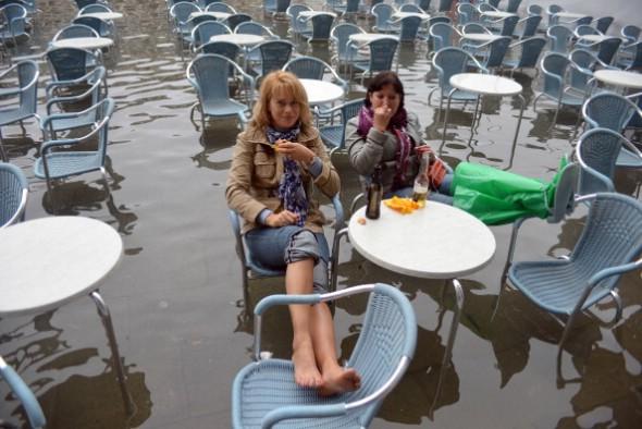 Turister har slagit sig ner vid ett kafé på den översvämmade Markusplatsen i Venedig under en storm den 27 oktober. (Foto: Andrea Pattaro/AFP/Getty Images)

