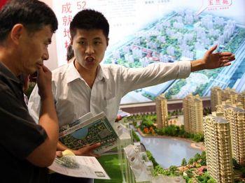 En försäljare på husmässan Shanghai Real Estate Trade Fair visar upp egendom för en potentiell köpare i Shanghai, Kina. (Foto:China Photos/Getty Images)