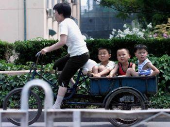 En kvinna trampar på ordentligt när hon kör tre unga pojkar på sin cykel genom en av Peking gator. (Goh Chai Hin/AFP/Getty Images) 
