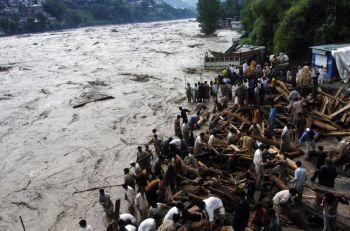 Pakistanier står intill översvämningarna som drabbade Muzaffarabads bostadsområde den 30 juli. (Foto: Sajjad Qayyum/AFP/Getty Images)