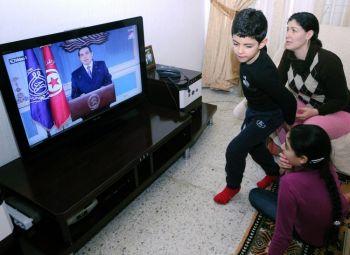 En tunisisk familj ser på ett tv-tal av president Zine el-Abidine Ben Ali. I ett försök att stoppa de allt starkare protesterna i landet lovade Ben Ali att avgå år 2014. Men experter tvivlar på att Ben Ali kommer att hålla sitt löfte. (Foto: Fethi Belaid/AFP/Getty Images)