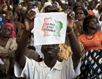 En ivoriansk man visar ett meddelande på franska på en bit tyg: "Fred är möjligt" när 5000 ivorianer samlats den 27 mars på kulturpalatset i Abidjan för att be om seger och fred. (Foto: Jean-Philippe Ksiazek / Getty Images)
