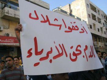Demonstrerande syrianer i staden Banias håller upp ett plakat på arabiska med budskapet: Stoppa det oskyldiga blodbadet, den 26 april då de gick ut på gatorna och krävde slutet för president Bashar al-Assads regim. (Foto: AFP/Getty Images)

