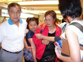 Shao Yuhua (mitten) brister i gråt när hon förenas med sin make (vänster) efter en veckas fångenskap hos de kinesiska myndigheterna. (Foto: Daina Lee/ Epoch Times)