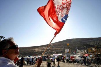 En man viftar med en flagga medan han väntar på undsättningen av de instängda gruvarbetarna från San José-gruvan nära Copiapo i Chile den 12 oktober (Foto: Hector Retamal/AFP/Getty Images)
