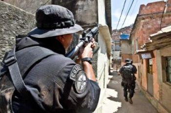 Kriget fortsätter: Specialstyrka under samordnad aktion; en polisman täcker sina kollegor när de patrullerar i slumområdet Morro do Alemao den 29 november i Rio de Janeiro, Brasilien. Polisen rensade kloakerna under Rios utbredda slumområden på måndagen på jakt efter hundratals knarkhandlare som flydde under en aldrig tidigare skådad militär aktion i ’favelas’ (slummen) som ledde till beslag av 40 ton narkotika, men få arresteringar (Foto: Jefferson Bernardes/AFP/Getty Images)