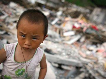 En ungt jordbävningsoffer står i ruinerna av sitt hus, 4 juni 2008, Shifang, Sichuanprovinsen. Mycket av de pengar som donerats för att hjälpa de drabbade nådde aldrig fram. (Foto: Andrew Wong/Getty Images)