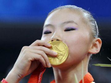 Kinas He Kexin kysser sin guldmedalj efter att ha vunnit damernas barr i finalen den 18 augusti. Yang Yilin, även hon från Kina, vann brons. De båda kinesiska gymnasterna har nu hamnat mitt i en kontrovers angående deras ålder.(Foto: KAZUHIRO NOGI/AFP/Getty Images)
