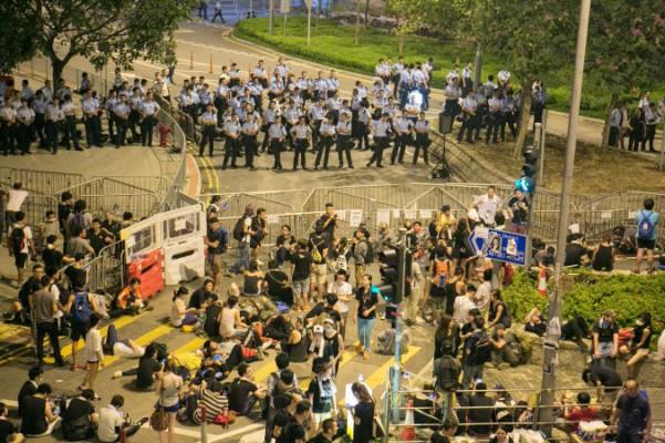 Hongkongpolisen står på vakt framför tusentals prodemokratiska demonstranter framför Kinesiska folkets befrielsearmés byggnad i Hongkong, 2 oktober 2014. (Benjamin Chasteen/Epoch Times)
